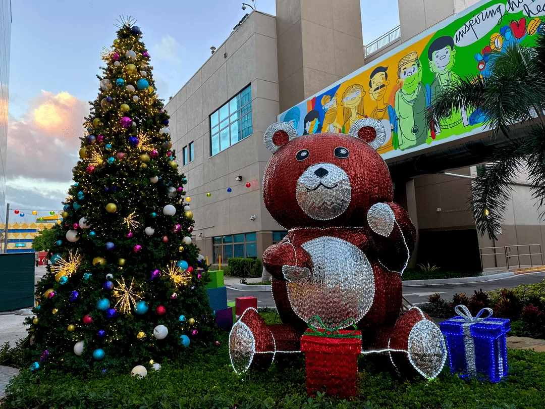 Giant teddy bear beside a decorated tree in a commercial holiday display