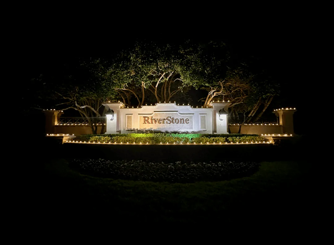 Riverstone community entrance sign with uplit trees at night