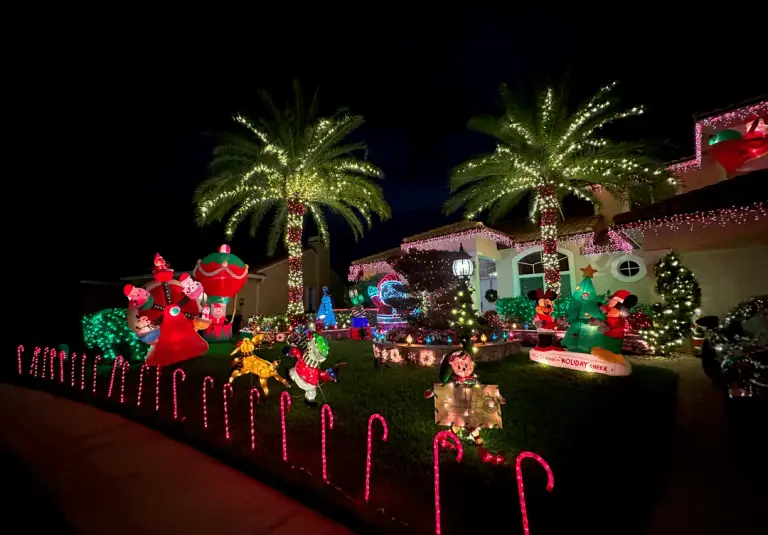 Festive South Florida home with candy-cane path lights, inflatable characters, and palm trees wrapped in holiday lights